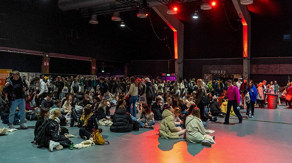 Erstsemesterempfang: Erstsemester sitzen in der Halle des Kulturzentrums Schlachthof auf dem Boden:.