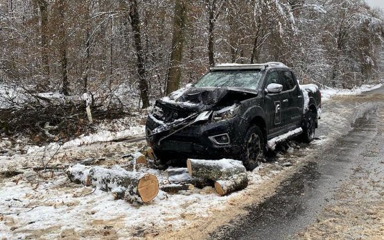 Auto auf Landstraße auf das Äste und Bäume gekracht sind.