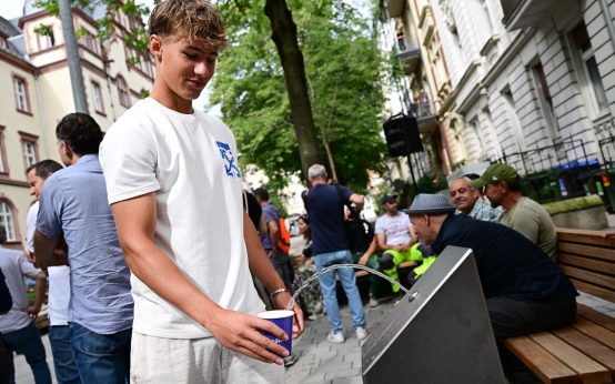 Hitzehilfe: Refill-Station in der Gerichtstraße, Jugendlicher füllt Becher auf.