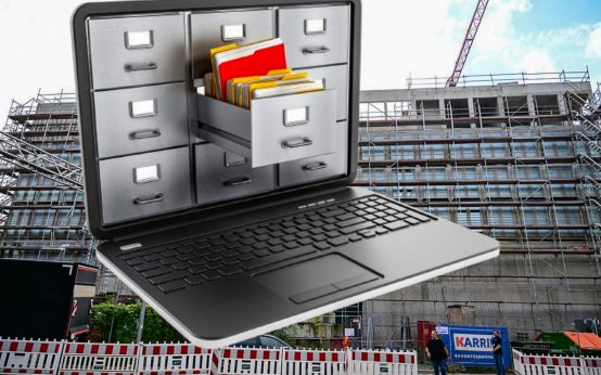 Baustelle im Hintergrund und Laptop im Vordergrund: Der hybride Bauantrag startet.