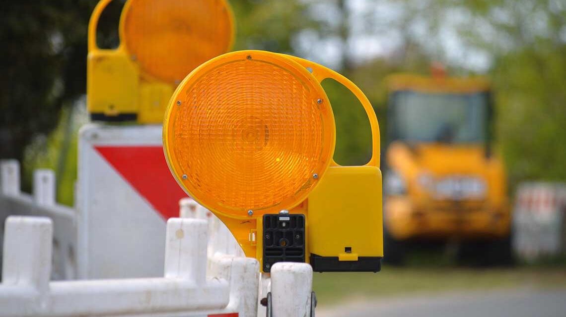 Baustellenabsperrung im Vordergrund, dahinter Baustellenfahrzeige in der Unschärfe.